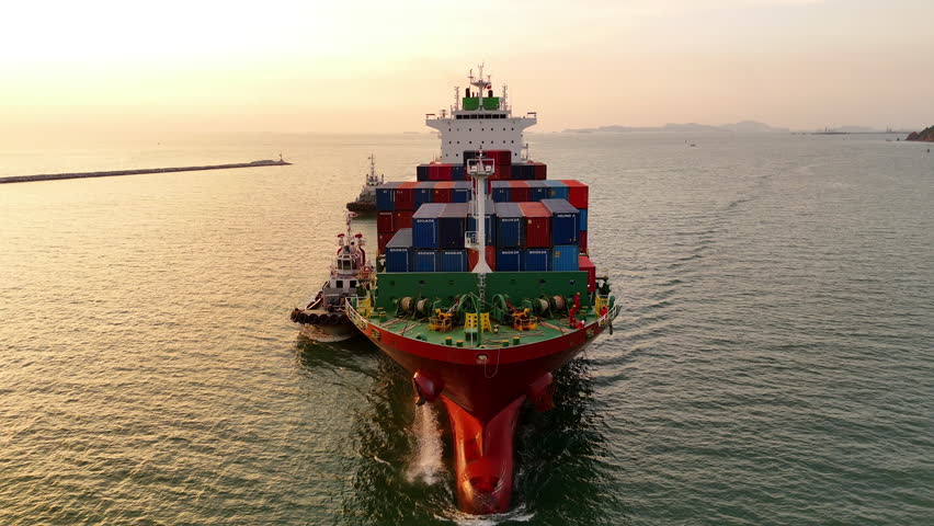 Cargo container ship at sunset carrying container and running out international container port customs shipyard sea port concept smart logistic service.