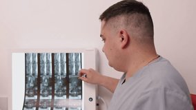 spine X-ray, doctor scrubs, X-ray analysis. Healthcare provider in scrubs carefully studies spine X-ray, highlighting important details during clinical review. - Powered by Shutterstock - Get 15% off with code: PIKWIZARD15