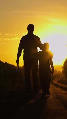 Family business, farmers. Dad teaches son how to farm. Farmer father walks with his son in sunflower field. Father, child walk around plantation. Dad child walks in nature against sun. Happy family.