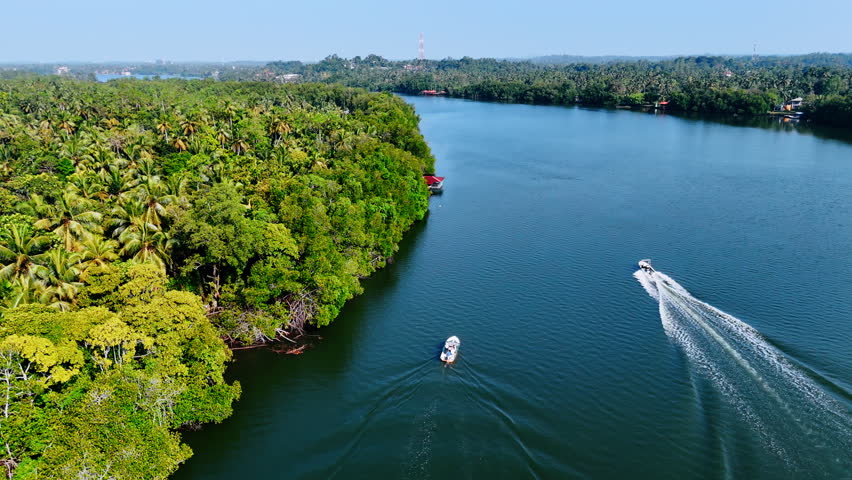 Two boats moving by the river between the picturesque banks. Beautiful tropical forests grow on the waterfront of Sri Lanka. Aerial view.