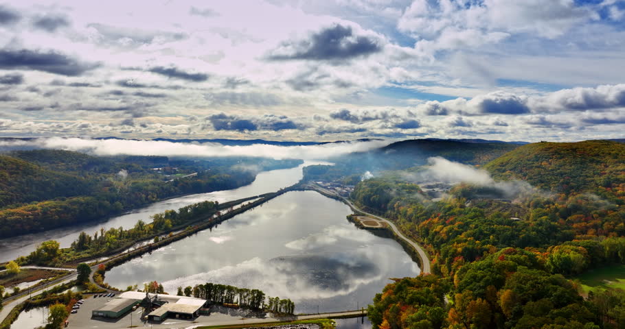 Lake Champlain in Vermont, New England, USA reflecting the overcast sky. Lush woods changing colors in autumn surround the waterscape. Aerial view.