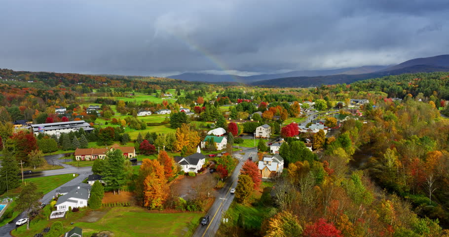 Lovely cozy cottages located in the picturesque nature. Autumn in Vermont, New England, USA. Overcast sky above the mountain range silhouette at backdrop.