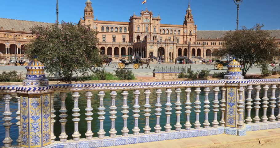 The Plaza de Espana, Spain square in Seville town, Andalusia, Spain. Ornate balustrade overlooking a plaza with a grand building and horse-drawn carriages.