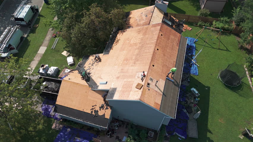 Roofers installing a new roof on an building. Wide drone shot view