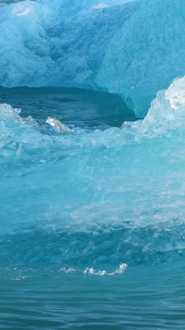 Vertical Screen: Pure blue ice in arctic. Icebergs breakaway from glacier in Iceland. Crystal clear blue ice floats in salt turquoise water. Shot for Social Media. Jokulsarlon Glacier Lagoon. 
