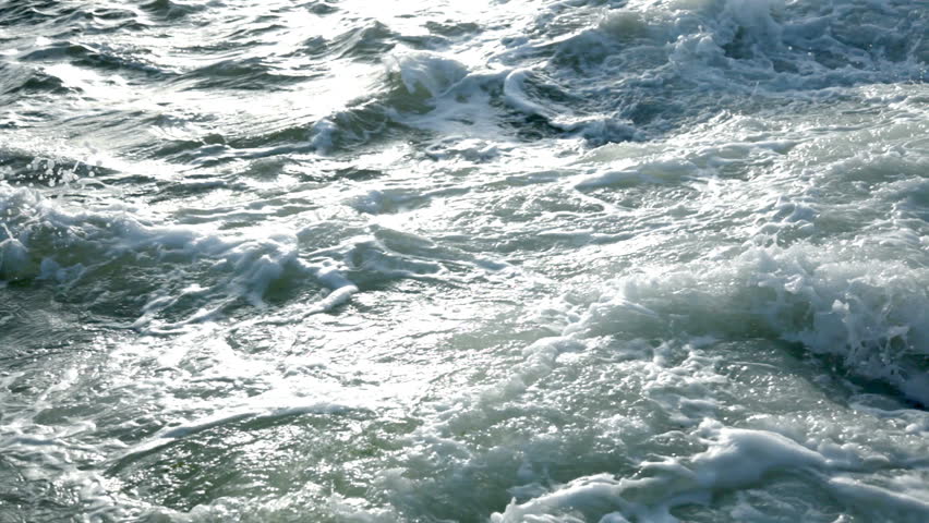 Dusk. Ocean waves crash on the coastal rocks and bubbling. Whirlpools. Spray.