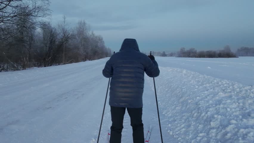 A skier skates along the road late at night.