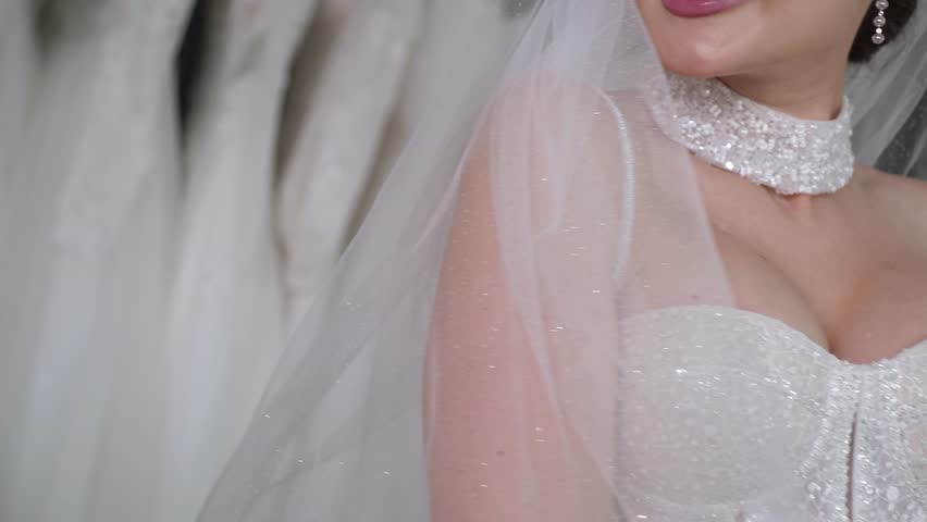 Close-up portrait of a beautiful young woman in a wedding dress with a deep neckline with a veil in a wedding salon. A model in a wedding dress poses for the camera.