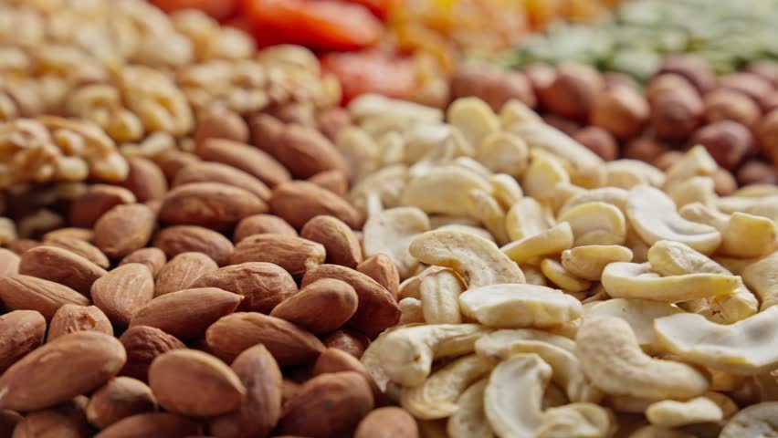 Mixed dried fruits and nuts rotates. Top view of different snacks. Healthy protein food. Vegan food. Close up in 4K, UHD
