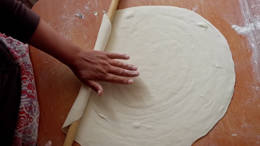 Baker rolling pastry dough on wooden surface, revealing delicate artisan techniques in professional kitchen workspace with precise slow-motion cinematography