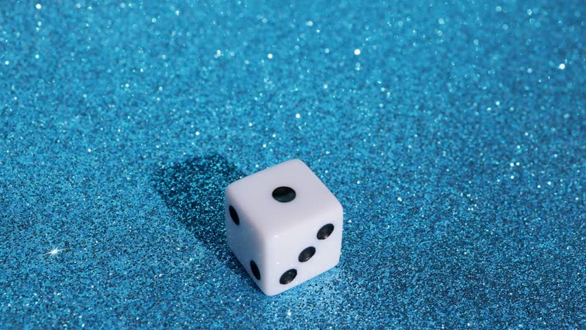 Footage of a man rolling a dice on a blue glittery background showing the number one on the dice