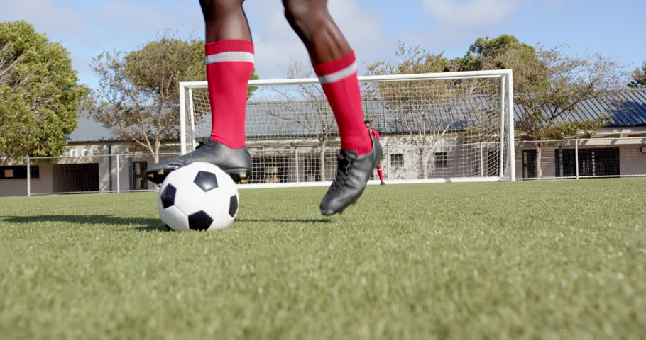 Kicking soccer ball on field, african american male player wearing black cleats, copy space. football, sports, african american male athlete, action, footwear, team