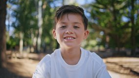 Cheerful kid looking camera at sunshine forest portrait. Happy smiling child feeling positive having fun at sunny greenery park closeup. Brunette small boy enjoying holidays spending weekend outdoors - Powered by Shutterstock - Get 15% off with code: PIKWIZARD15