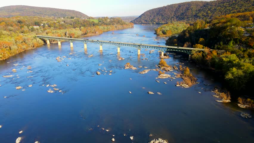 Fall on the Potomac River in Harpers Ferry National Park. View of the highway bridge from a drone. Camera movement along the river.
