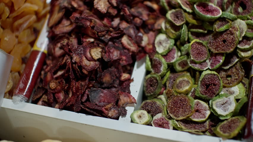 Close-up slow-motion view capturing dehydrated fruits like dried figs, displaying vibrant colors and textures against rustic market background