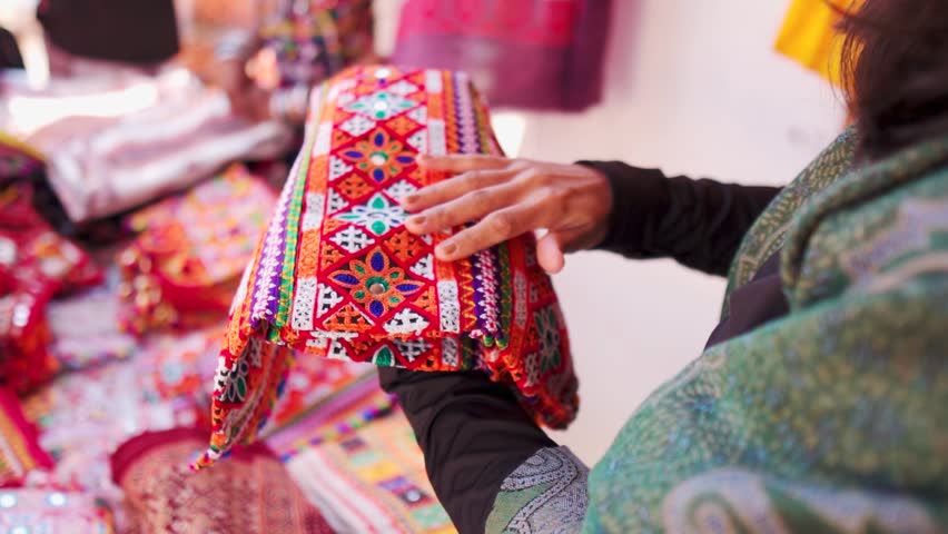 Close up shot of woman buying handicraft clothes from Rann Utsav market in Kutch, Gujarat, India. Beautiful Kutchi Handicraft arctician designer cloth in local street market. Shopping concept. 