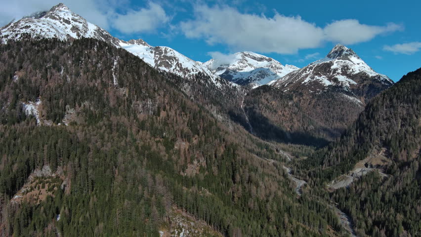 Aerial view of forest on snow mountain range landscape. Alps mountains, Austria, 4k
