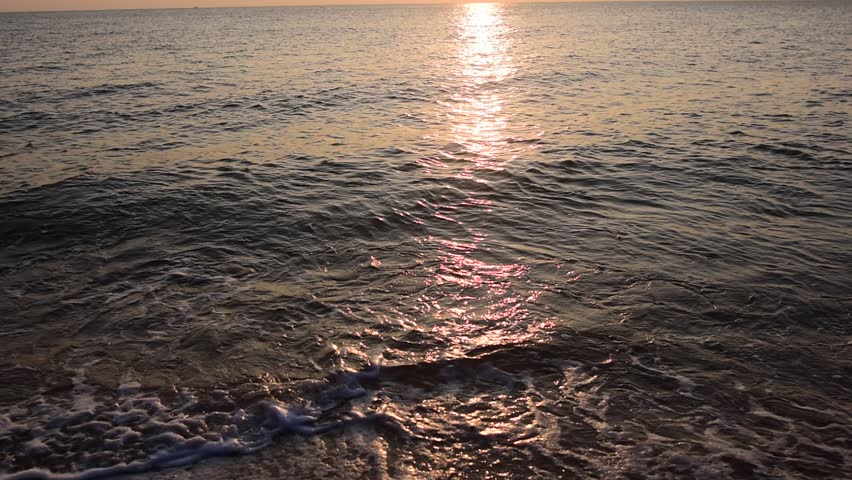 abstract washed-out sea with wave and foam, shoreline in the sunset light, glare and bokeh, sunset on the beach, Footsteps in the sand on the beach