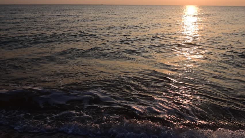 abstract washed-out sea with wave and foam, shoreline in the sunset light, glare and bokeh, sunset on the beach, Footsteps in the sand on the beach