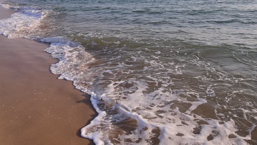 abstract washed-out sea with wave and foam, shoreline in the sunset light, glare and bokeh, sunset on the beach, Footsteps in the sand on the beach