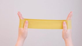 Hands stretching yellow fitness elastic band on gray background close-up. - Powered by Shutterstock - Get 15% off with code: PIKWIZARD15