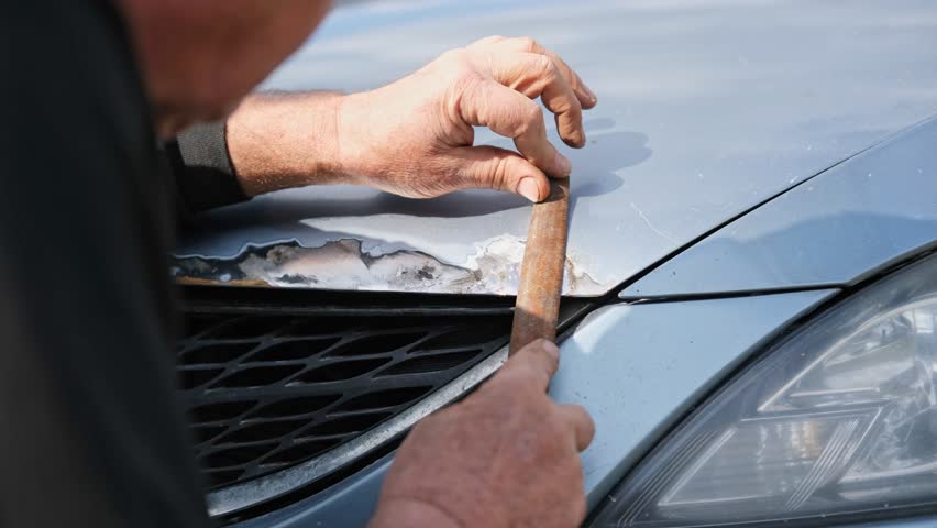 Car body shop. Repair man processes the welding seam using an angle grinder on replaced car part. Professional Body master grind old paint and rust. Rust damage. Rusting car. Hands with tool close-up