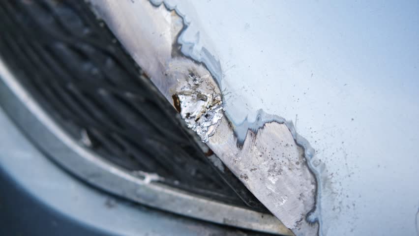 Car body shop. Repair man processes the welding seam using an angle grinder on replaced car part. Professional Body master grind old paint and rust. Rust damage. Rusting car. Hands with tool close-up