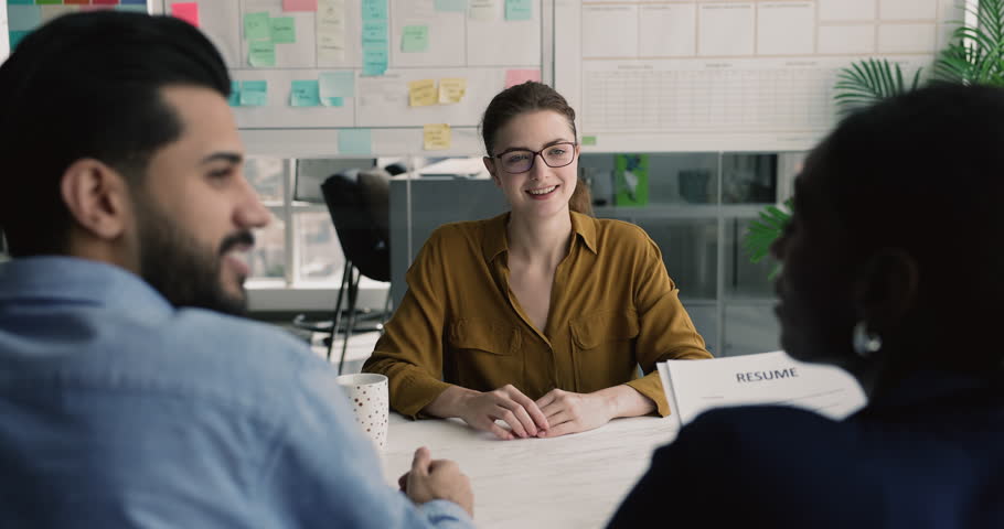 Hiring, new job opportunities. Young 30s attractive applicant answers questions asked by two multiethnic recruiting managers holding curriculum vitae, interviewing vacancy candidate during interview