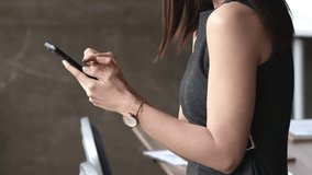 Close up cropped shot of businesswoman holding modern smartphone in office, using new mobile business application, share messages, enjoy chat, typing e-mail or browsing wireless internet on cellphone - Powered by Shutterstock - Get 15% off with code: PIKWIZARD15