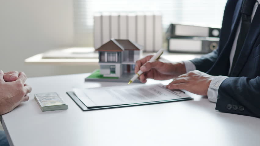 Business people seller explain and calculate to buyer or mortgage and signing agreement paperwork for loan financial for real estate house properties.