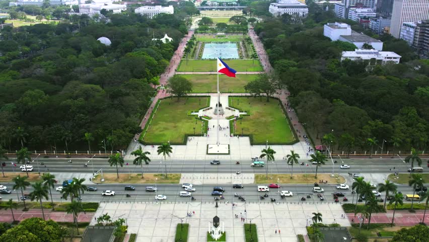 Aerial shot of Rizal Park, also known as Luneta Park, located in the heart of Manila, Philippines. The iconic Philippine flag stands tall at the center
