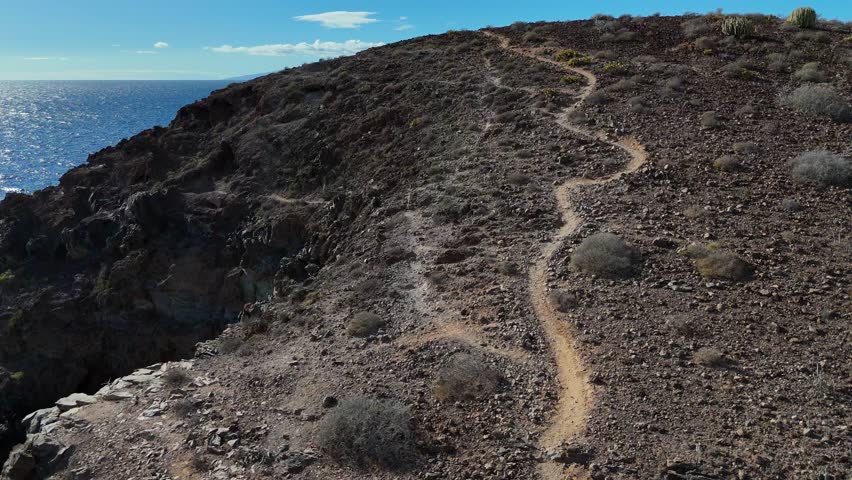 A rugged volcanic trail on Tenerife, Canary Islands, overlooks the ocean and La Gomera