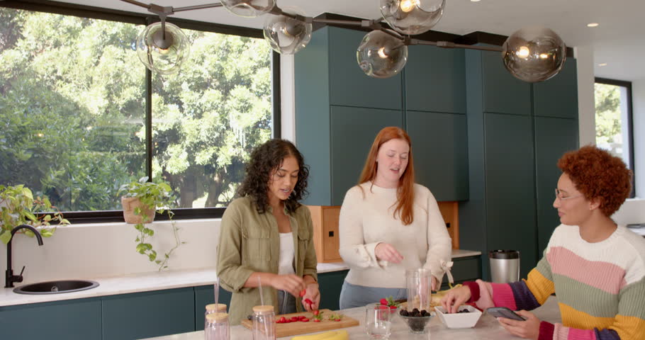 Preparing fruit and smoothies, diverse female friends enjoying time together in kitchen. Healthy, cooking, friendship, fun, lifestyle, fresh