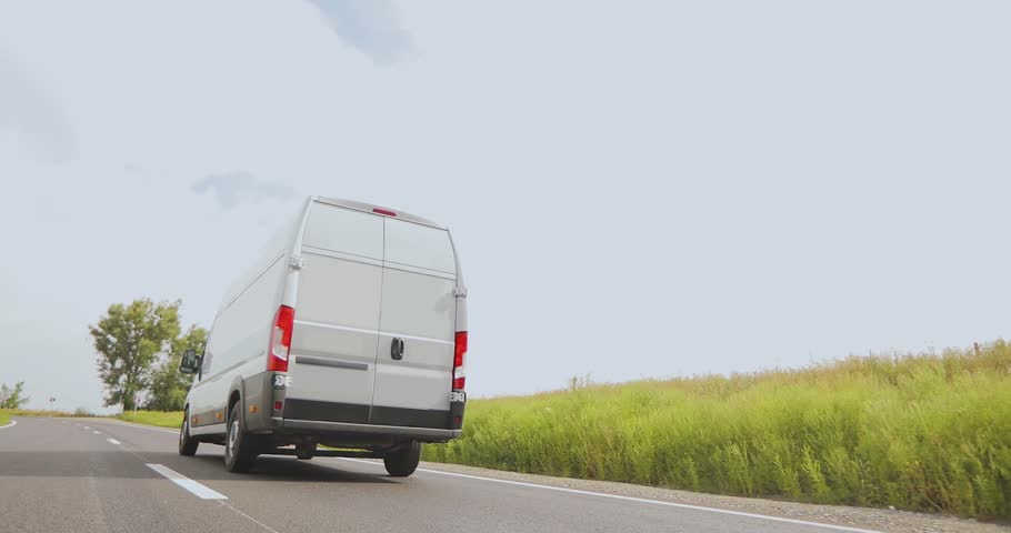  White delivery van delivers goods fast on the highway. White delivery van or service van driving down the highway on a sunny day. Fast delivery or service concept.
