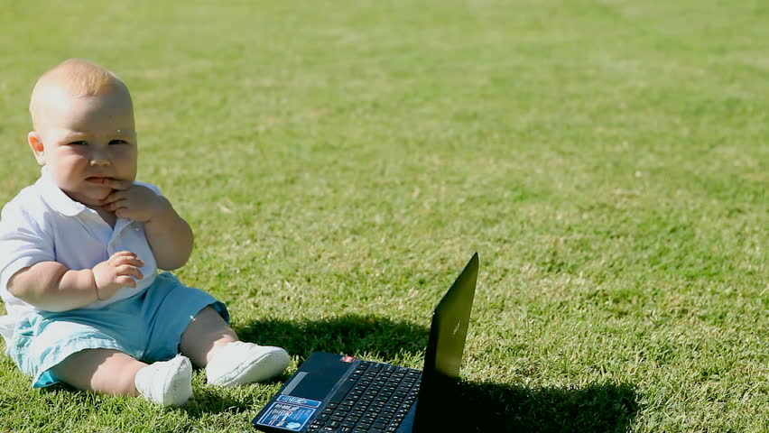 The baby on the grass with a laptop