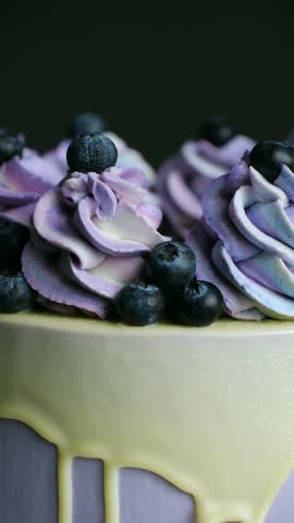 Organic fresh blueberries and sweet buttercream swirls on birthday cake closeup. Healthy dessert with classic decor on bakery shop display