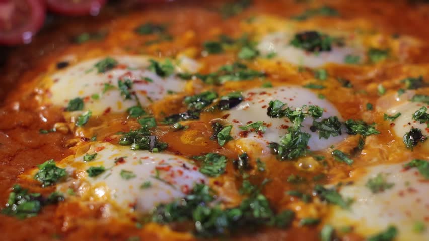 A closeup detailed shot of hot shakshuka with steam, showing its texture and details