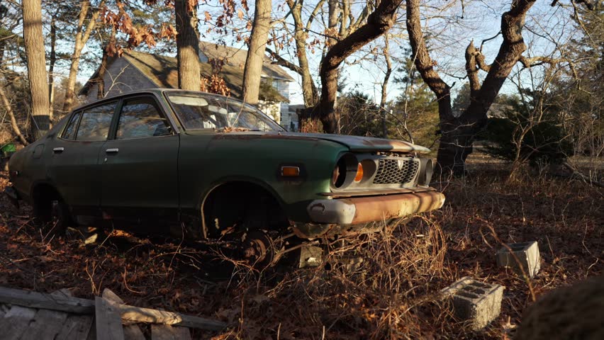 slow motion shot of an abandon car in the woods near an old house