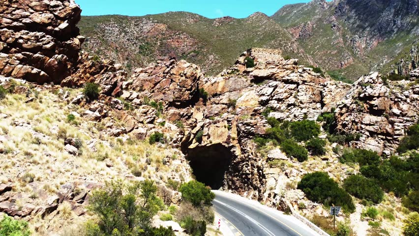 Tarmac road under the small tunnel and Old English Fort on top of rocks. In Cogmanskloof close to Montagu.