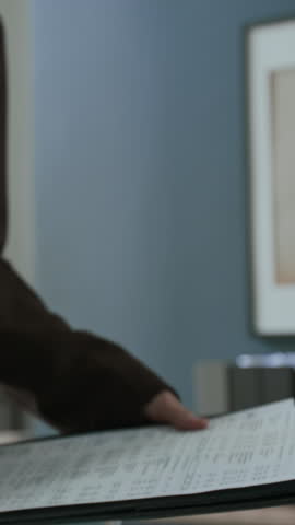 Vertical close-up shot of hands of unrecognizable woman holding financial report and shaking hands with business consultant during meeting in office