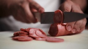Close-up stock footage of a chef cutting pepperoni into even slices with a sharp knife. Ideal for videos about food preparation, cooking tutorials, or recipes - Powered by Shutterstock - Get 15% off with code: PIKWIZARD15