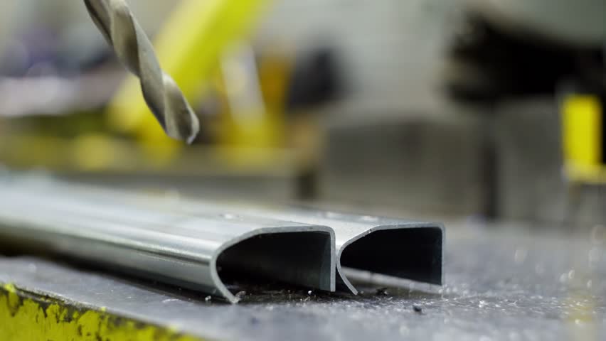 A close-up of a drill drilling metal structures. Slow motion video of metal cutting. Industrial factory. High quality 4k footage