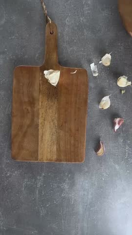 Female hands peel garlic by classic crush method with knife. Overhead view.