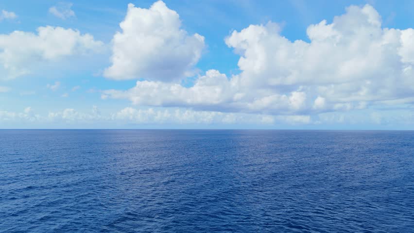Gentle aerial dolly of vast blue ocean under a clear sky, calm and peaceful sea surface