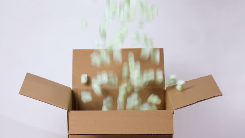 Green packing peanuts falling into brown corrugated box, shot in HD video