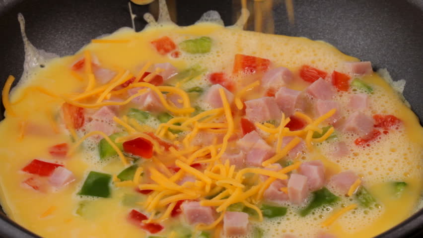 Closeup HD video of an omelette being cooked in a frying pan, peppers, ham and
