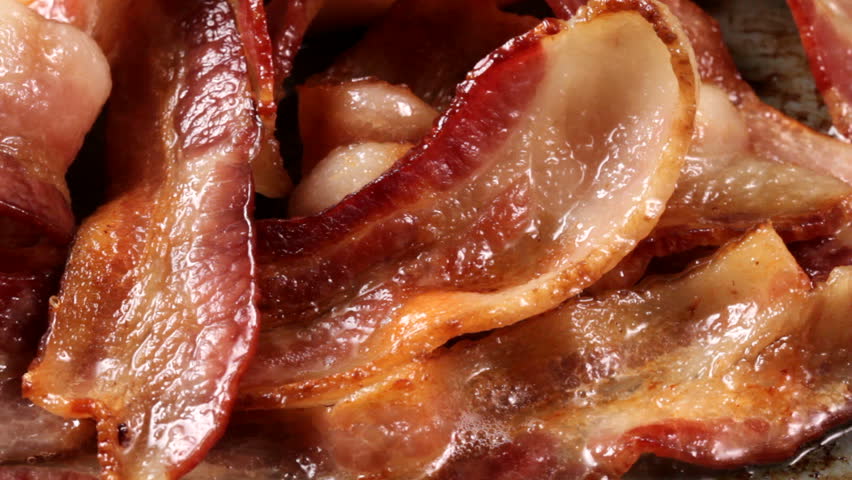 Several closeup HD video clips of cooking bacon are cut together