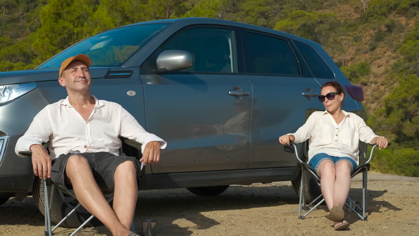 Family travelers relax in folding chair. A view of family traveler enjoy the free time together in the folding chairs by the car during nature camping.