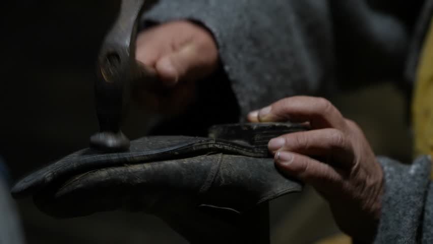 Cobbler Hammering Old Shoe for Restoration, Traditional Craft of Repairing in Poor Rural Workshop