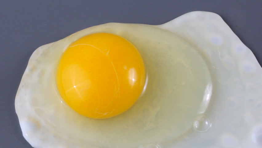 Close up of hands breaking egg over griddle, cooking sunny side up